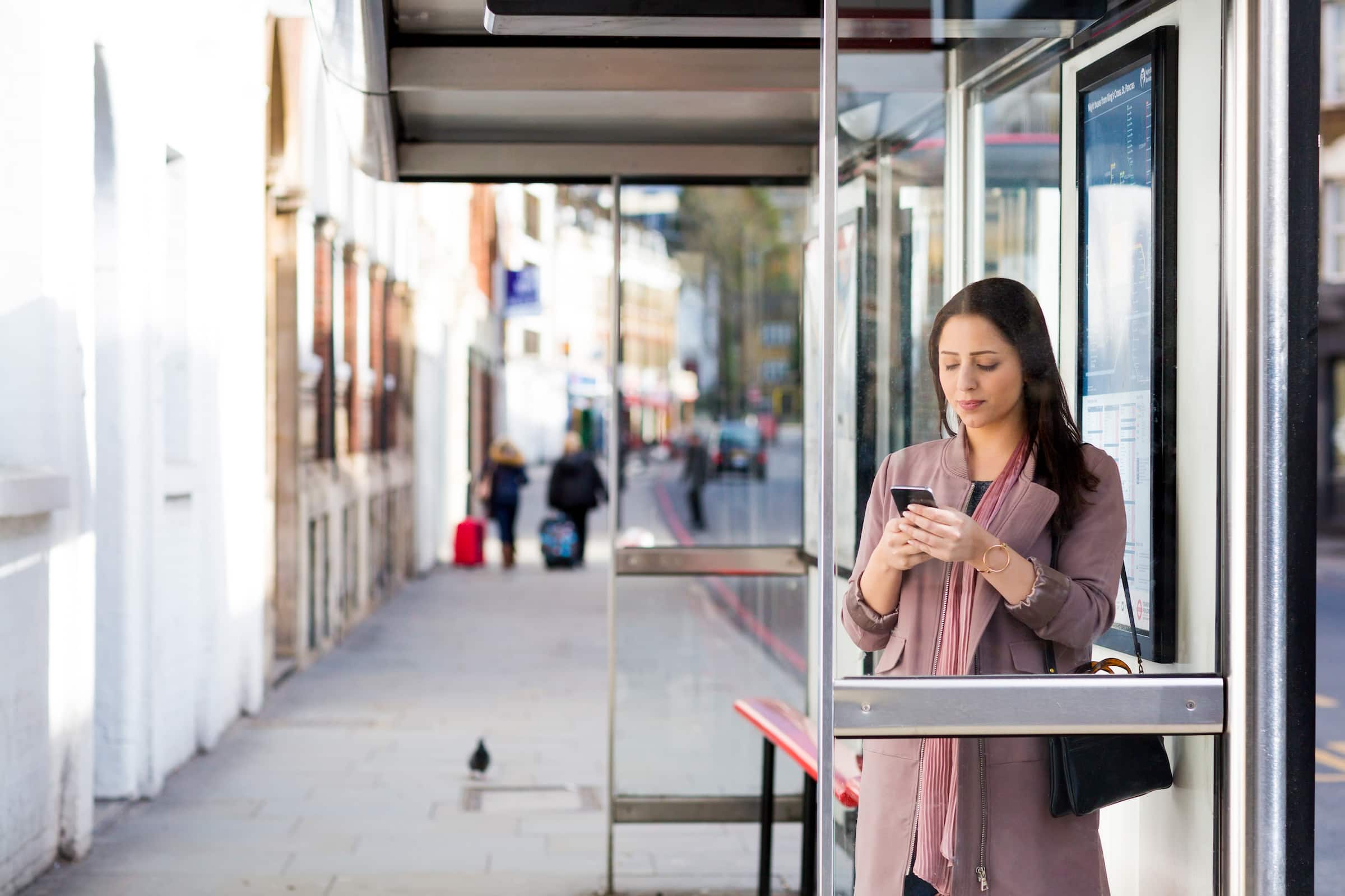 A person standing outside of a professional services building using Xero accounting software on their mobile.