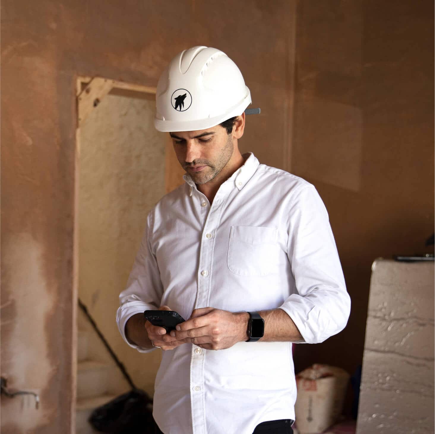 A small business owner on a building site enters the costs of materials into Xero job costing software on his mobile.